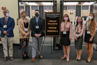 Flagler College students standing in front of the entrance to the Florida Undergraduate Research Conference