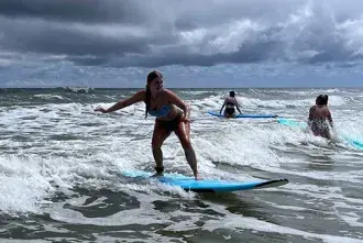Student in Sam McMillan's Adventure Literature class surfing at Vilano Beach