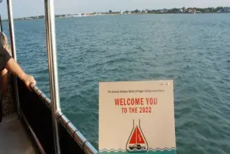 Someone is holding the Sunset Cruise invitation with water and a lighthouse in the background