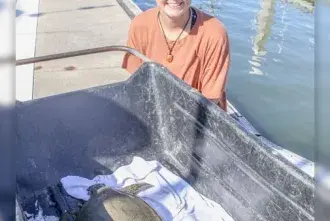 Flagler College students poses with a sea turtle 