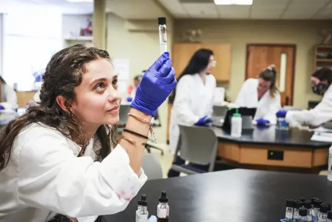 A Flagler College student holds a test tube.