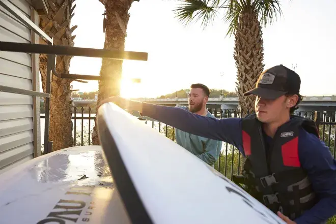 A student and staff member grabbing paddleboards to go out on the water