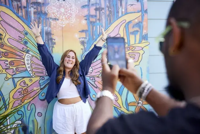 Student taking picture in front of a mural