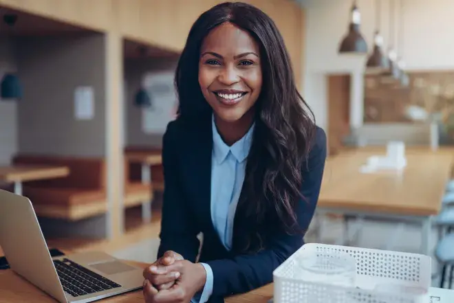 A student with a laptop smiles.