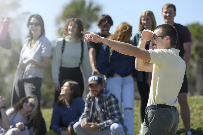 A professor and students standing out in the sun having an outside session