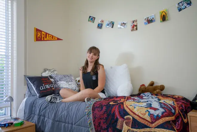 Student sitting on a bed in their room