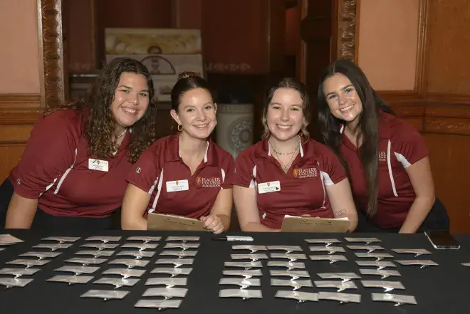 Four Flagler College students sit at a registration table.