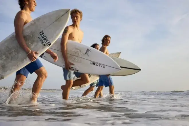 Image of students on the beach with surfboards