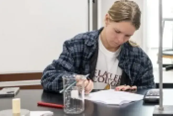 Student in lab writing on notebook