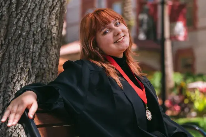 Student sitting on bench in cap and gown