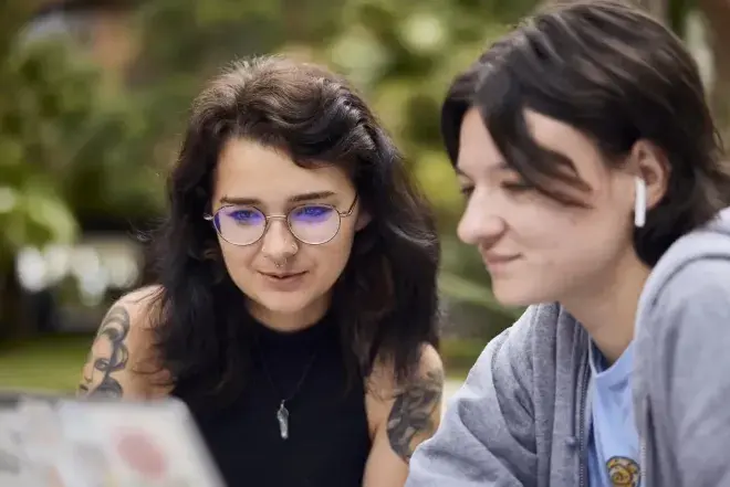 Students looking at laptop outside