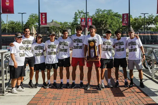 Men's Tennis Team posing together with the championship trophy