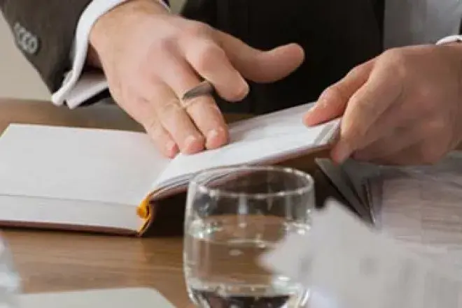 Economics Image.jpg Table filled with laptop, textbook papers and glasses of water.