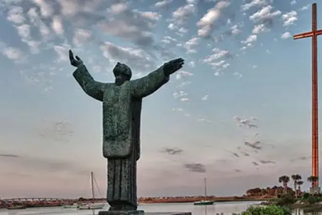 Praying statue with large cross in background
