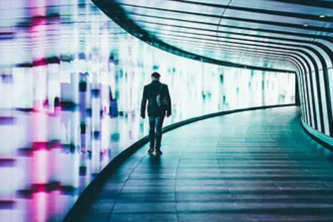 A man walks away through a well lit tunnel.