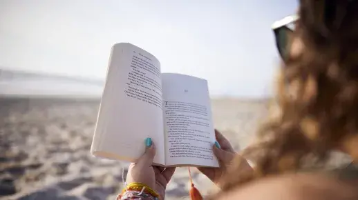 Student reading a book on the beach.