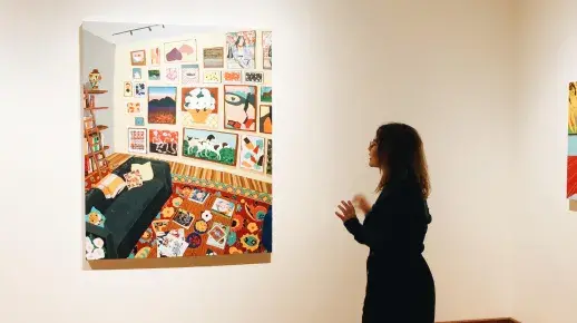 A faculty member examines hanging art work.