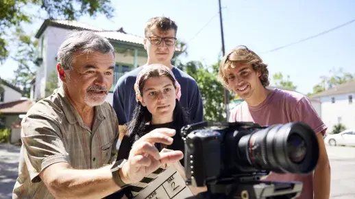 Professor and students reviewing video on the back of a camera.