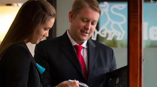 Two businesspeople consult their notes together.