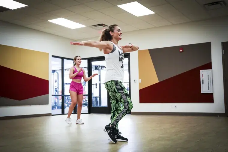 Two women participate in a fitness class.