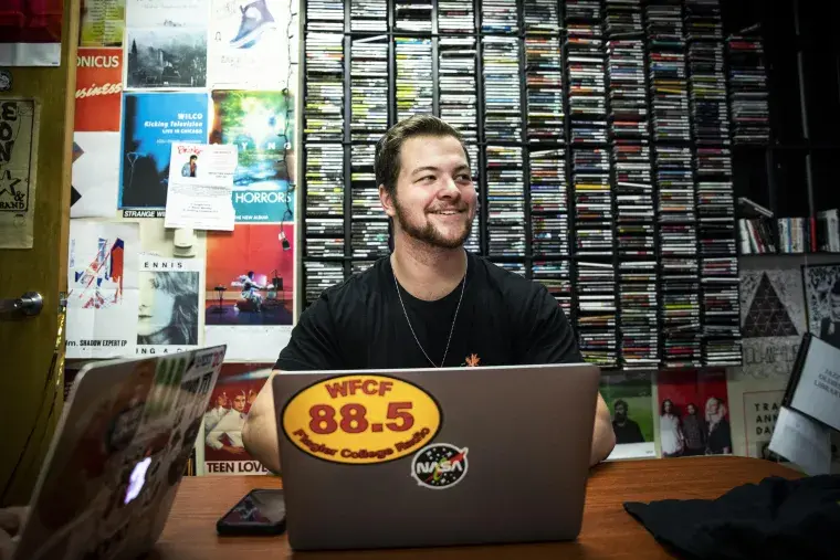A Flagler College student works in the Flagler College radio station offices.