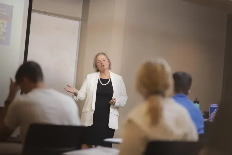 A faculty member is shown at a whiteboard.