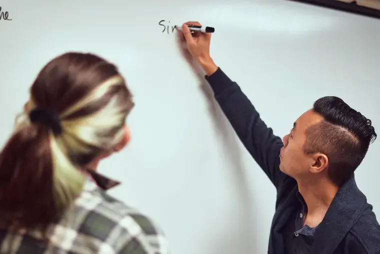 A Flagler College faculty member writes on a whiteboard.