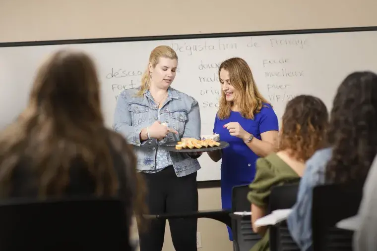 Flagler College students look at a tray of French food.
