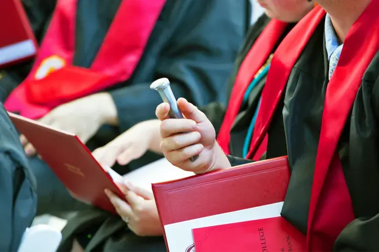 Spike and diploma in the hand of sitting graduate at a recent Commencement