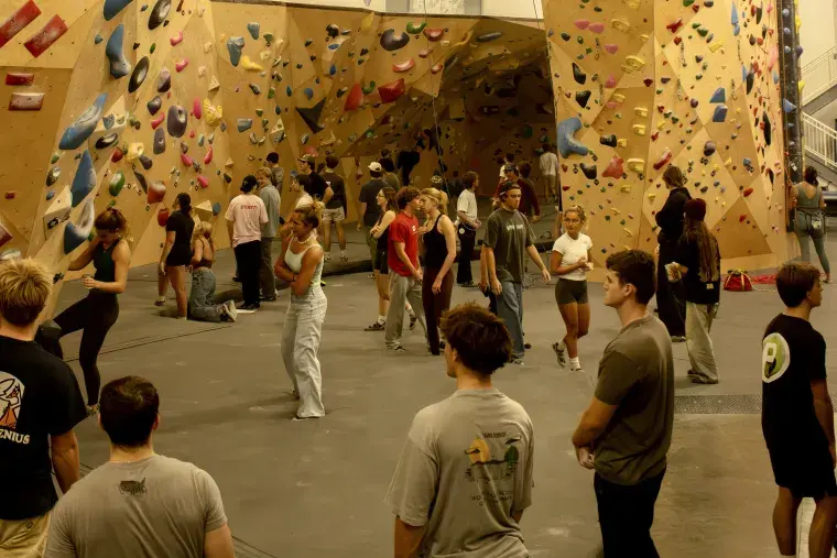 A collection of students stand ready to climb at Stone Climbing gym.