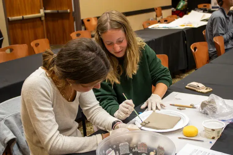 Two students working on a tile during a workshop on tile making