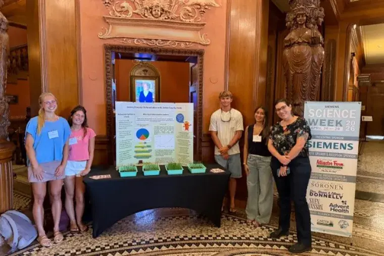 Students standing by their public research showcase table in the Ponce rotunda
