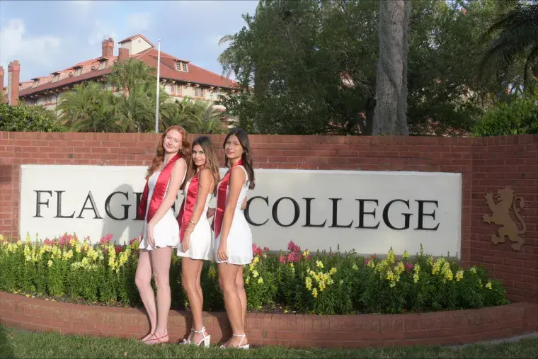 Maria Montero stands with friends in front of a Flagler College sign