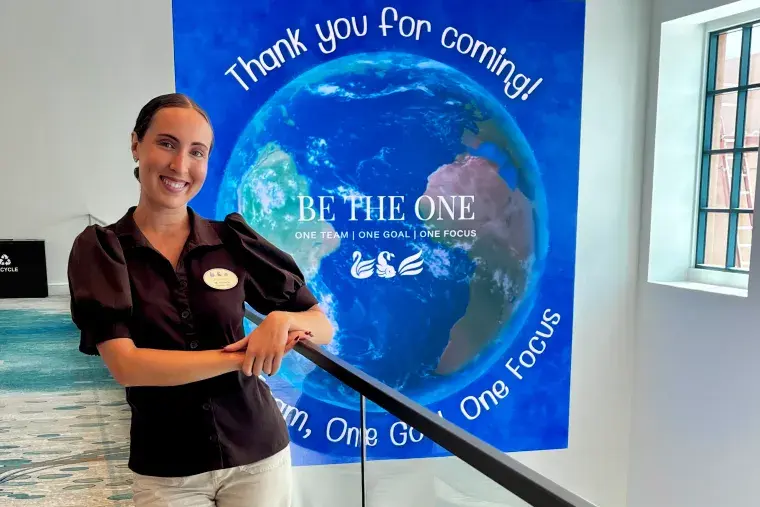 Addison Da Silva stands in front of a banner at the Swan and Dolphin resort