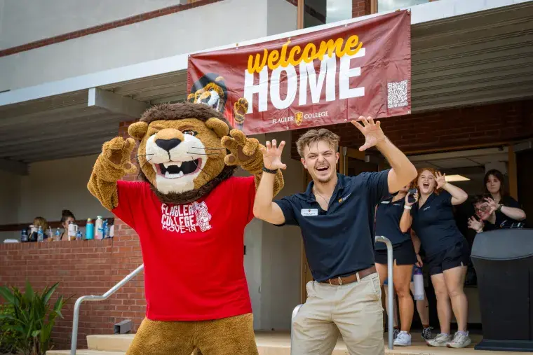 Joseph DelliSanti stands with Lewis The Lion while moving residents into Cedar Hall