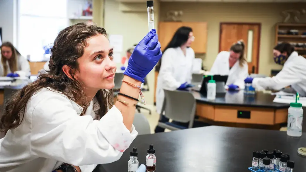 A Flagler College student is looking at a test tube in the science lab