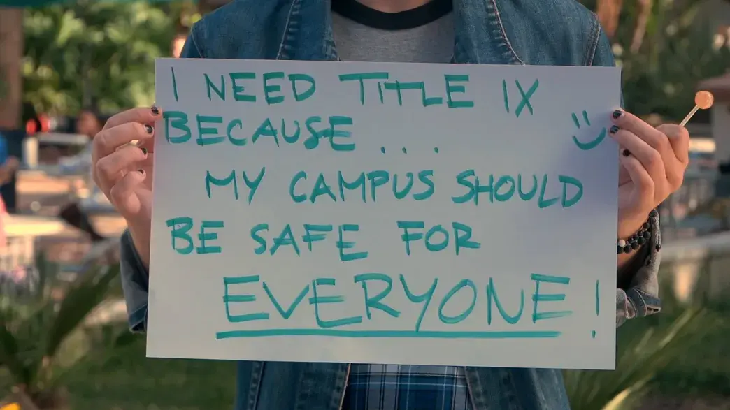 Student holds a sign that reads "I need Title IX because my campus should be safe for everyone"