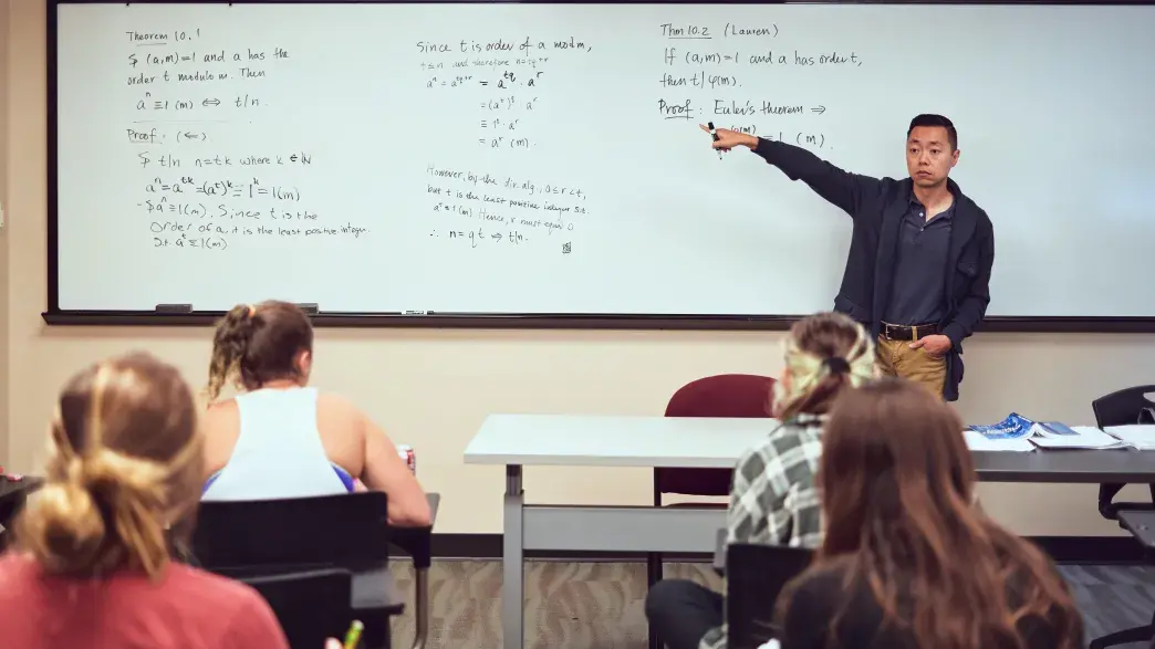 A Flagler College faculty member instructs using a white board.