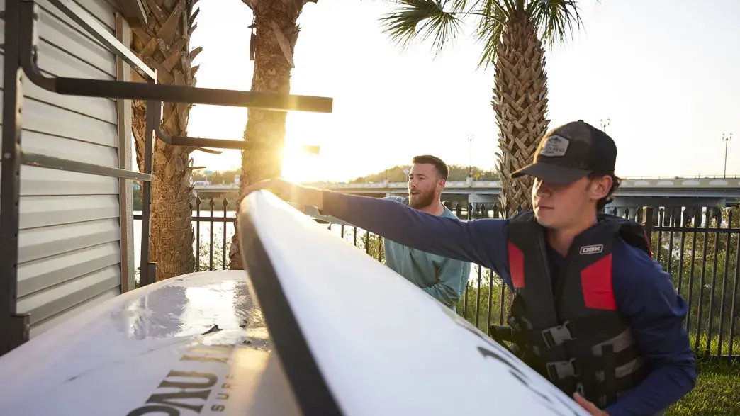 A student and staff member grabbing paddleboards to go out on the water