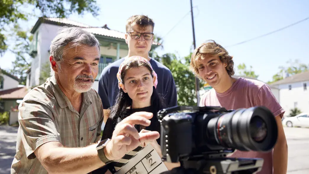 Professor and students reviewing video on the back of a camera.