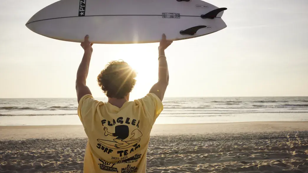 Student holding up surfboard