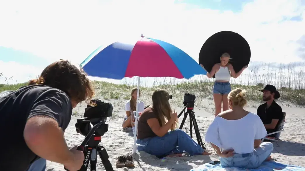 Image of Communications students filming on the beach