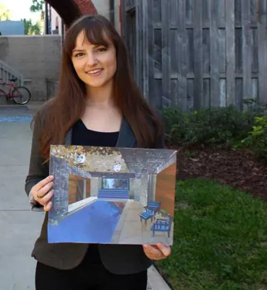 Student Miriam Raynolds holds up a piece of original artwork. 