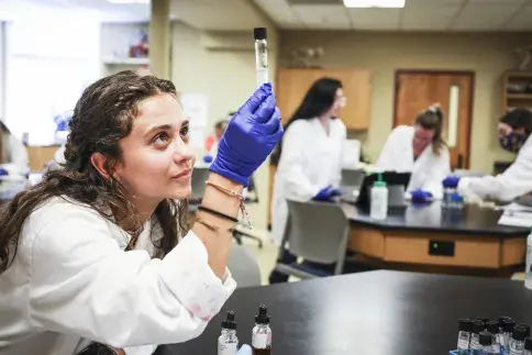 A Flagler College student holds a test tube.