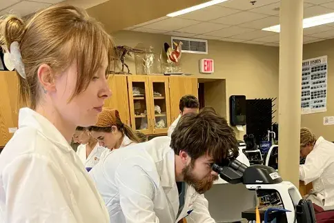 Two Flagler College students perform lab work.