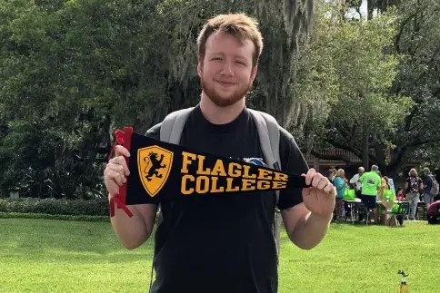 A Flagler College student holds up a Flagler pennant.