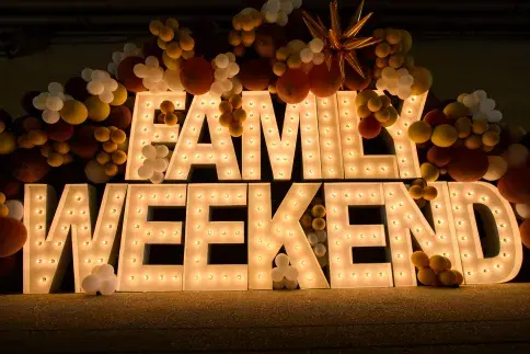 The words Family Weekend are shown surrounded by balloons.