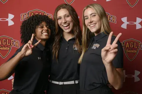 Three students smiling and showing peace signs