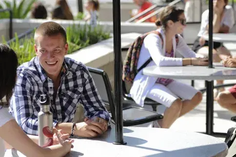 Four students sit at tables on outdoor patio of the Ringhaver Student Center. 