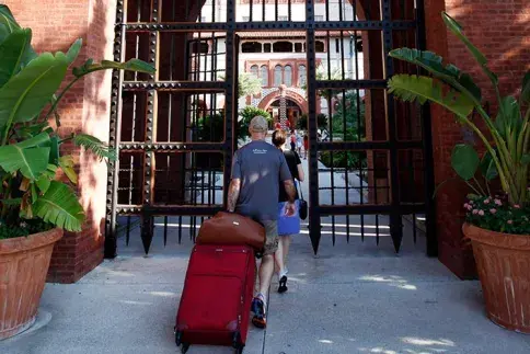 Students and parent roll suitcases through front gate of Ponce Hall